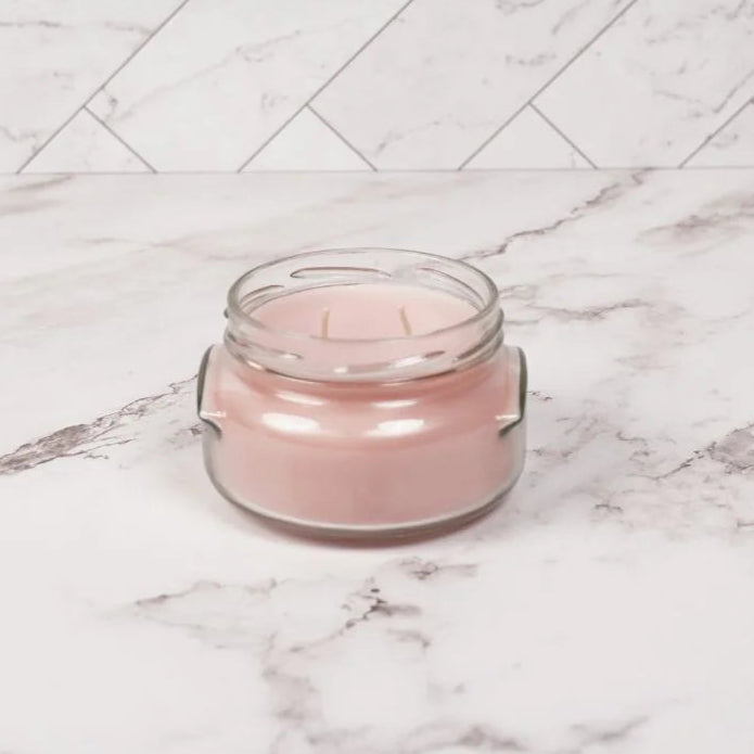 Pink glass jar on a marble surface with a white herringbone pattern in the background