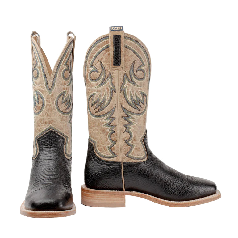 Pair of black and beige cowboy boots with intricate designs on a white background