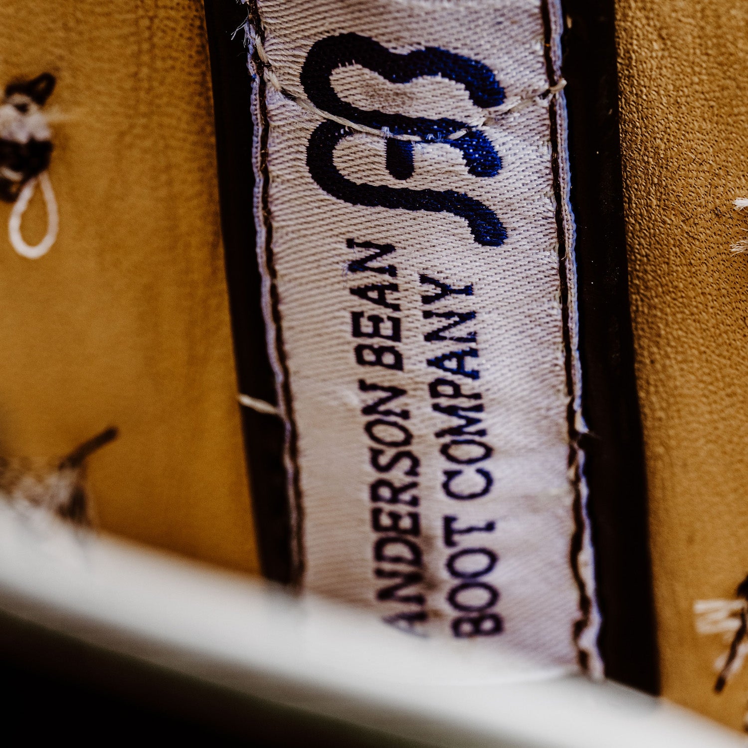 Close-up of a label on a brown leather boot with 'Anderson Bean Boot Company' text.