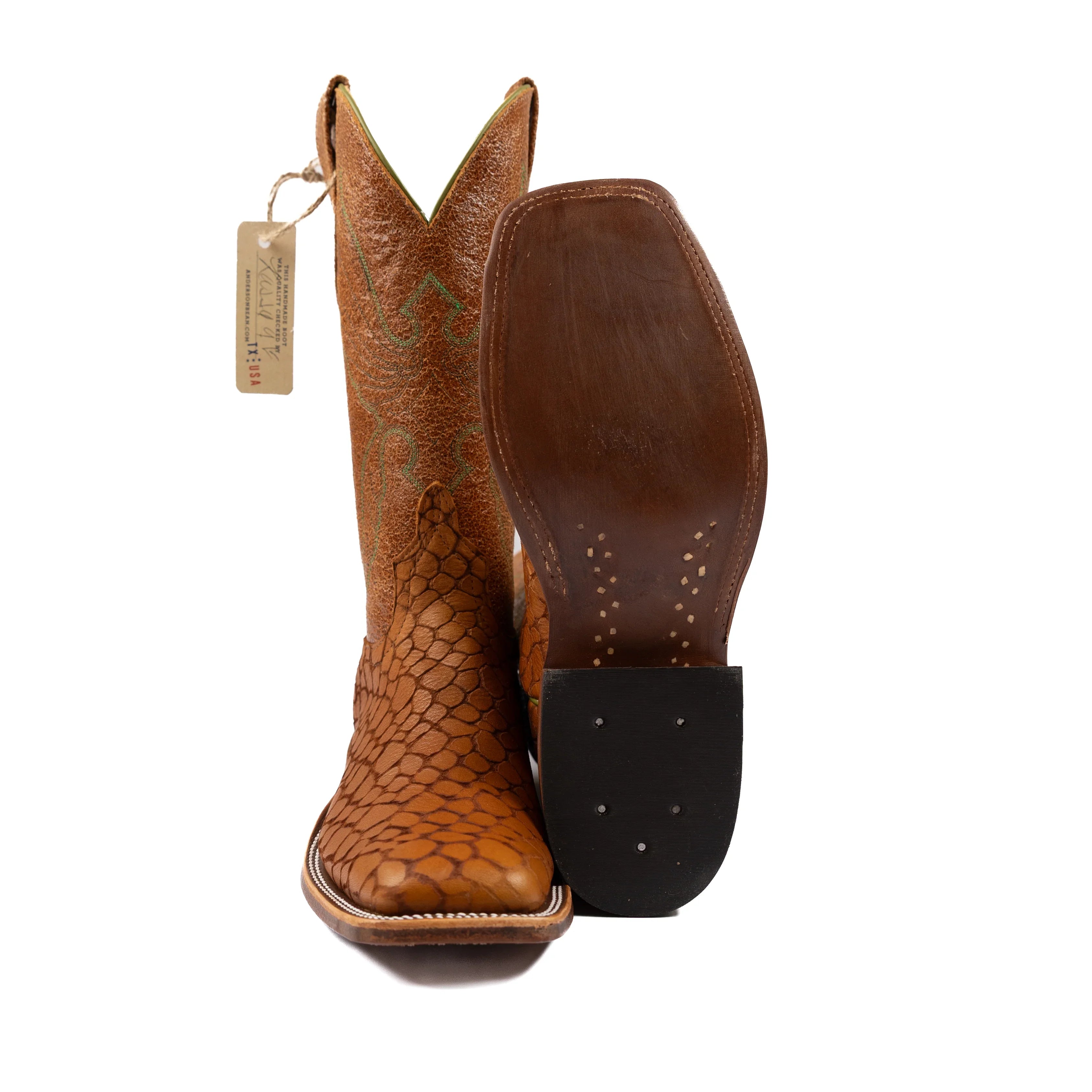 Brown cowboy boot with a textured sole on a white background