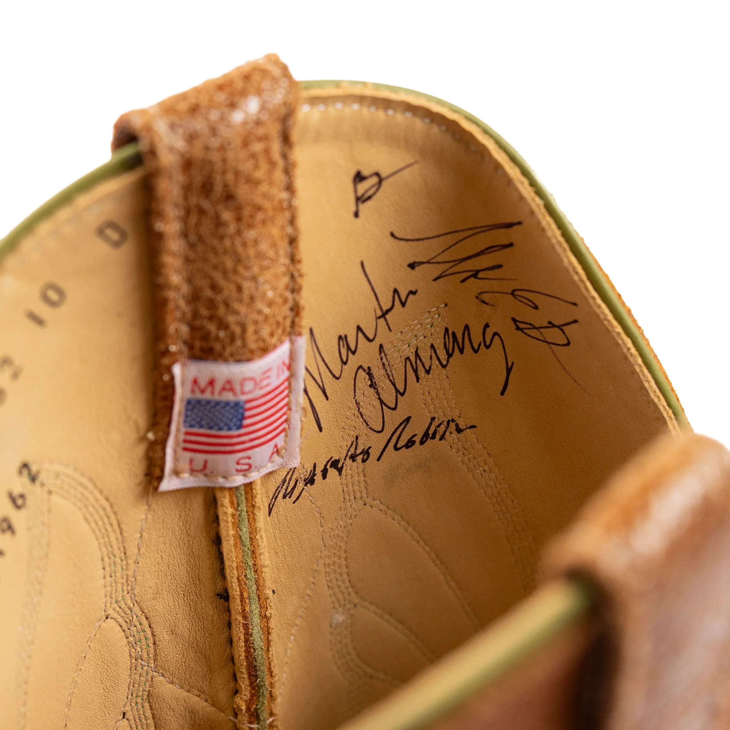 Close-up of a brown leather shoe with 'Made in USA' label and signature on a white background