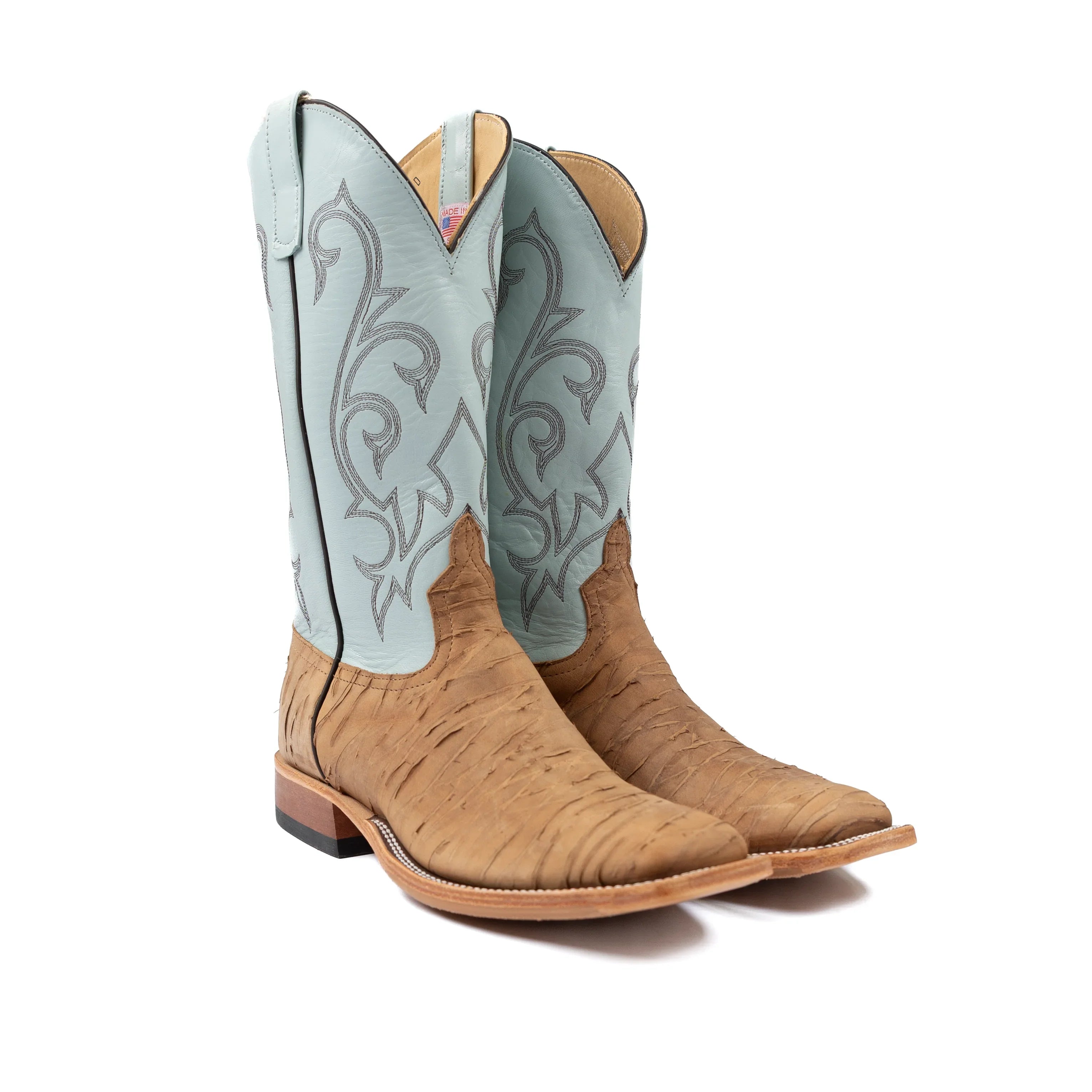 Tan cowboy boots with light blue inlays on a white background