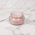 Pink glass jar on a marble surface with a white herringbone pattern in the background