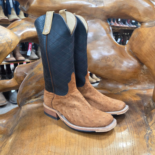 Pair of brown cowboy boots with black soles on a wooden horse statue.