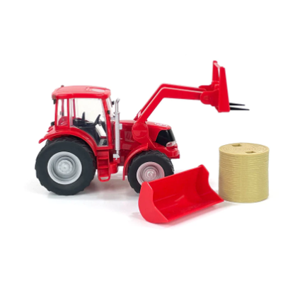Red toy tractor with front loader and straw bale on a white background