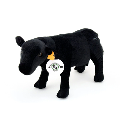 Black plush cow toy with a tag on a white background