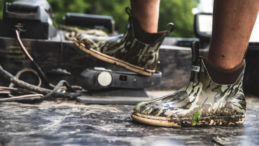 Person wearing camouflage rubber boots on a vehicle with a natural background